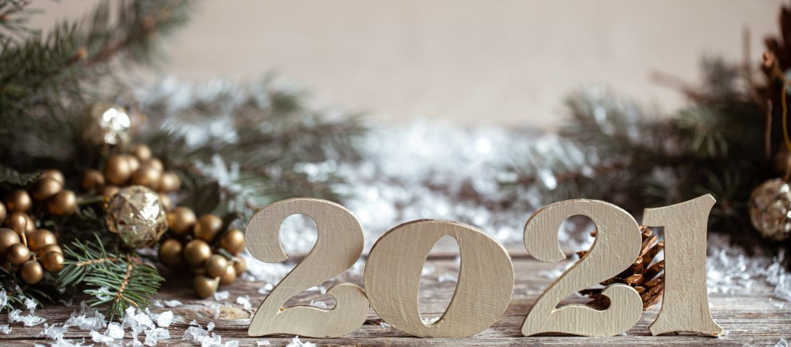 Cozy Christmas background with decorative wooden 2021 numbers on blurred background with lights.